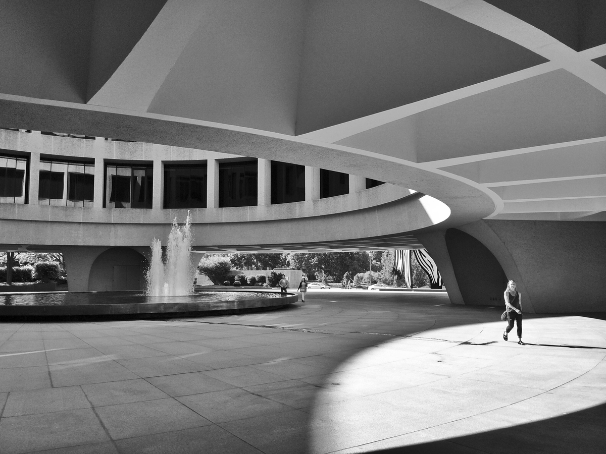 Grayscale shot of atrium with fountain and person walking in foreground Grayscale shot of atrium with fountain and person walking in foreground