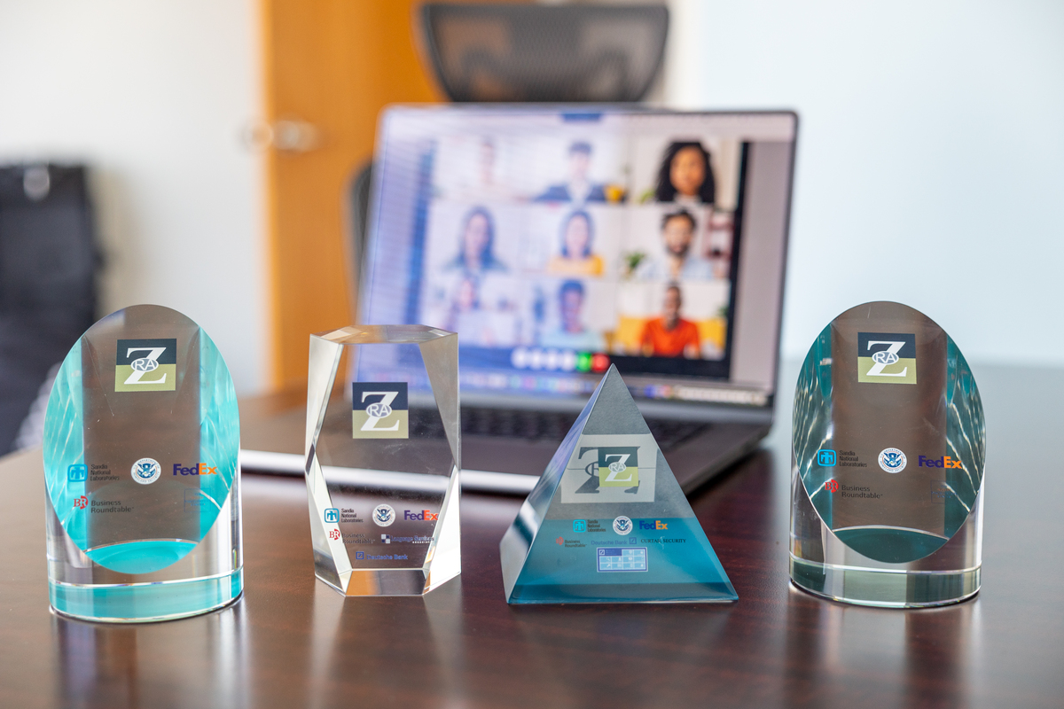 Four clear awards with ZRA and client logos in front of laptop with video conference Four clear awards with ZRA and client logos in front of laptop with video conference