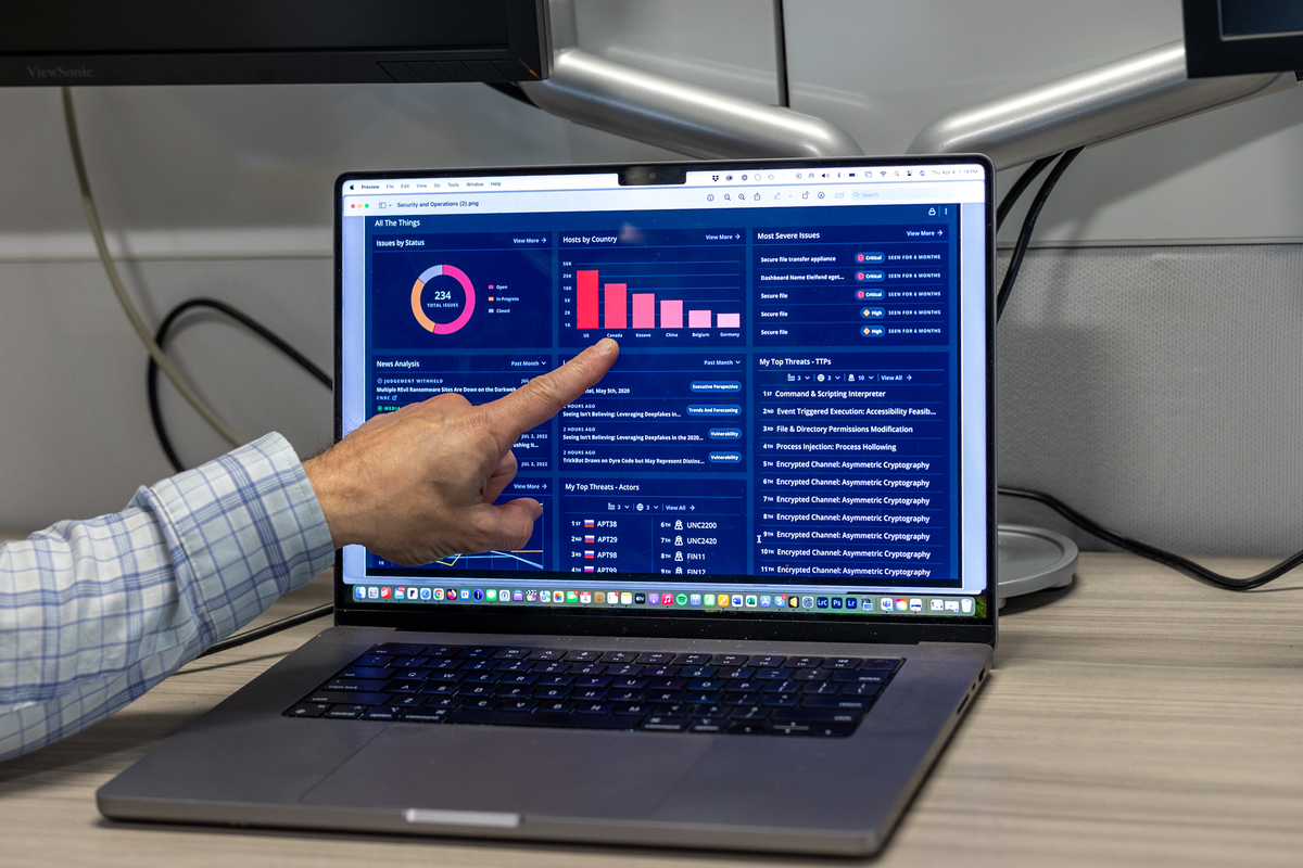 Laptop screen with blue dashboard and hand pointing to graphic Laptop screen with blue dashboard and hand pointing to graphic