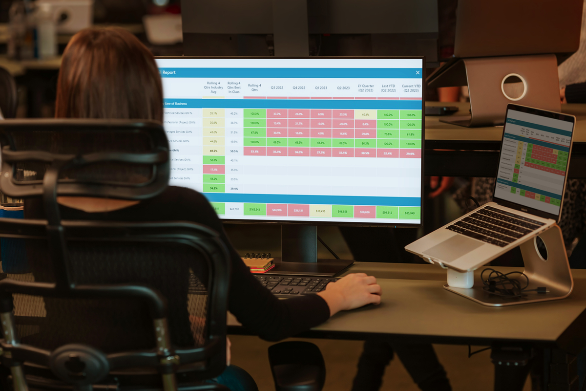 Woman seated at desk in front of monitor viewing spreadsheet with green, red, yellow, and gray cells Woman seated at desk in front of monitor viewing spreadsheet with green, red, yellow, and gray cells