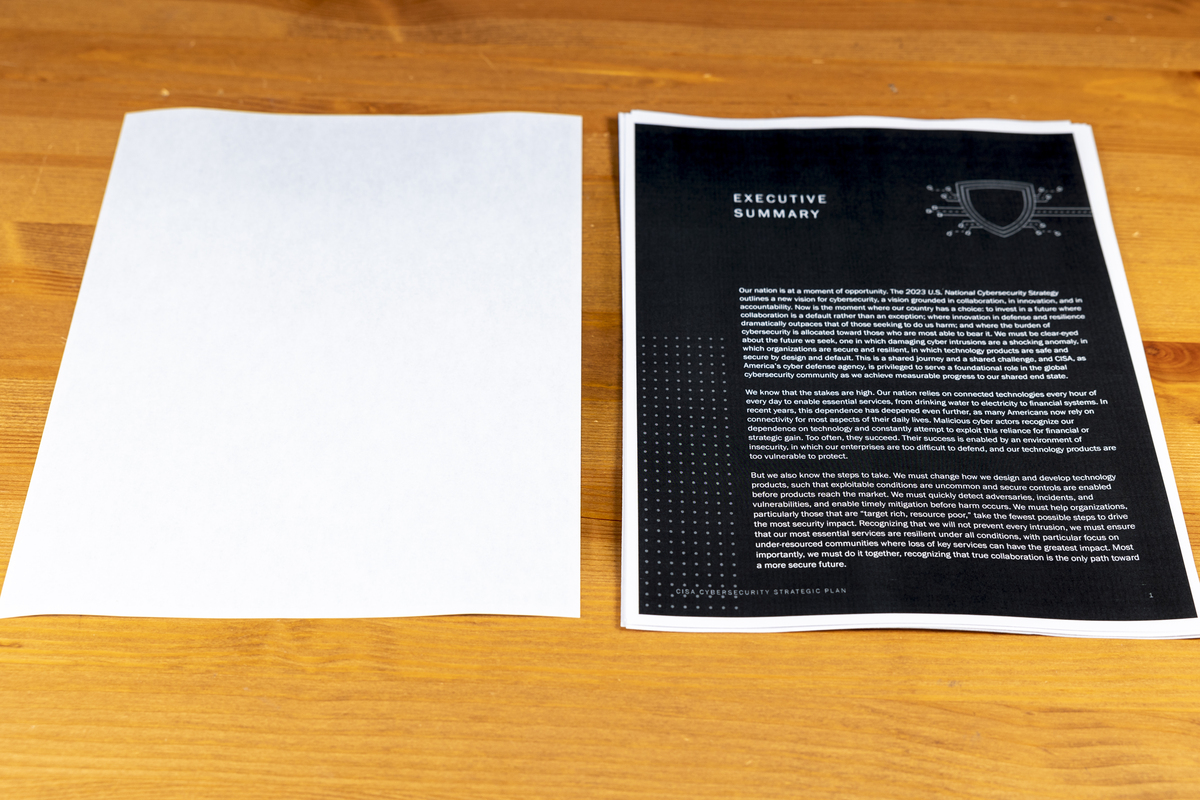 Printed CISA Cybersecurity Strategic Plan on black sheet with white text next to blank white sheet