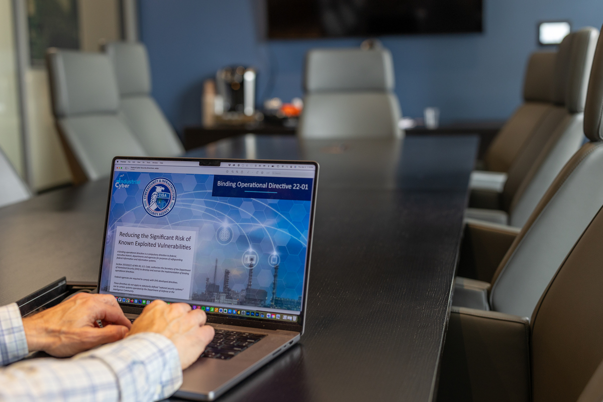 Conference room table with laptop showing CISA webpage with hands on keyboard
