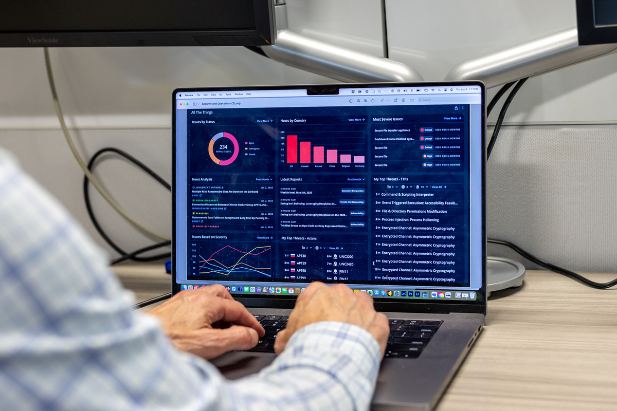 Laptop screen with dark blue dashboard and hand on keyboard
