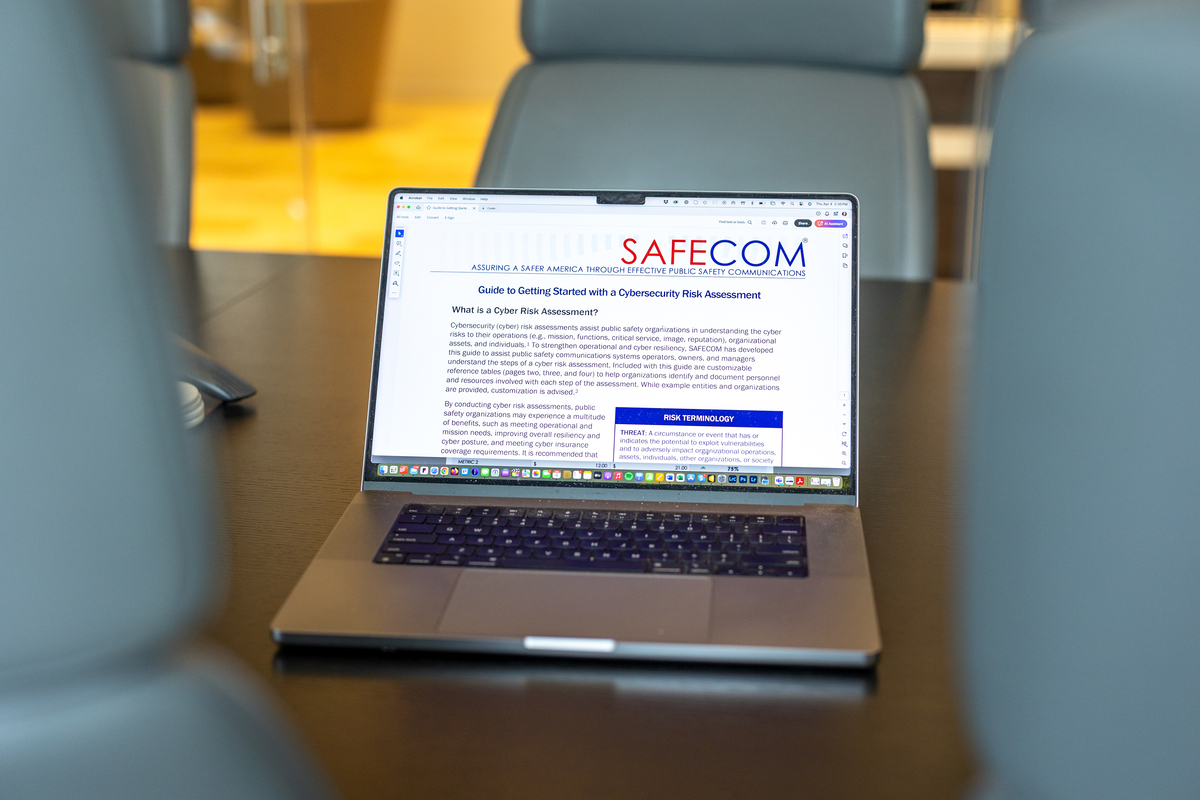 Conference room table with laptop screen showing SAFECOM webpage